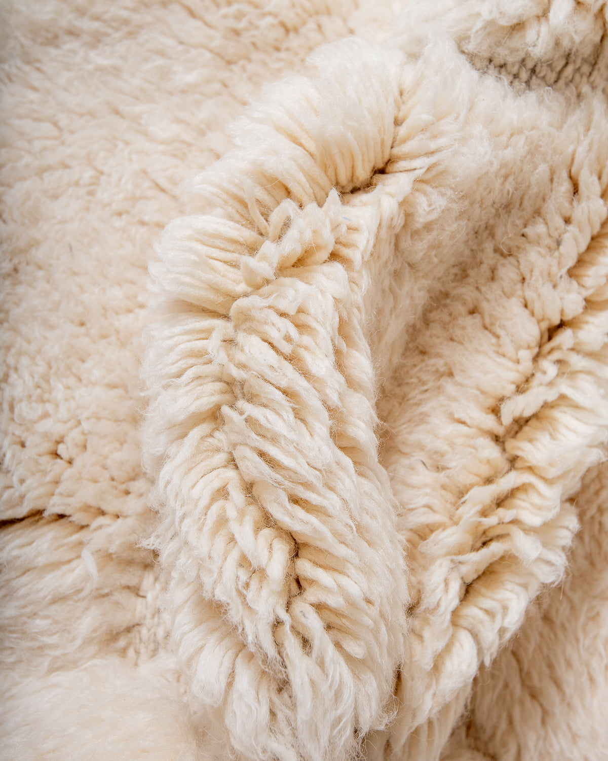 Thick fluffy wool of cream M'rirt rug bunched up to show texture.