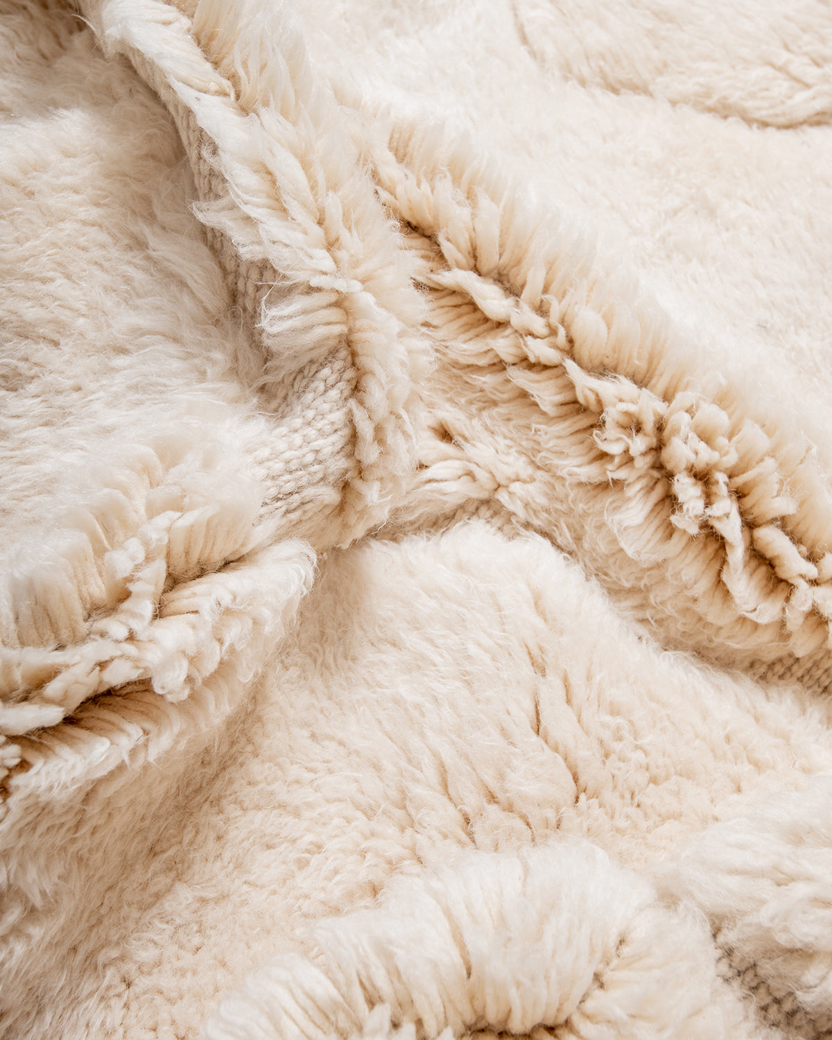 Detail of cream wool rug with design made of thickly knotted and flat woven areas.