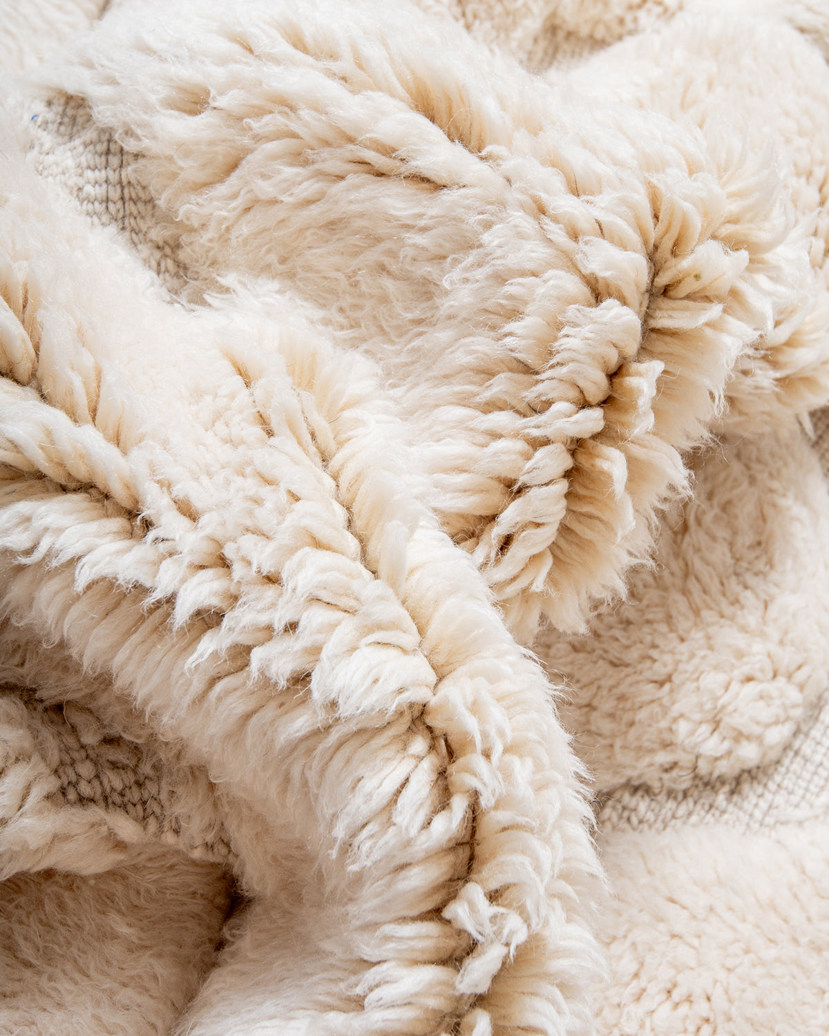 Thick fluffy wool of cream M'rirt rug bunched up to show texture.