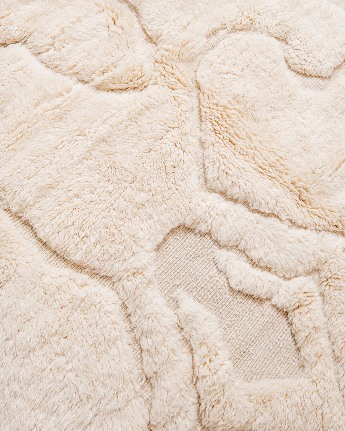 Detail of cream wool rug with design made of thickly knotted and flat woven areas.