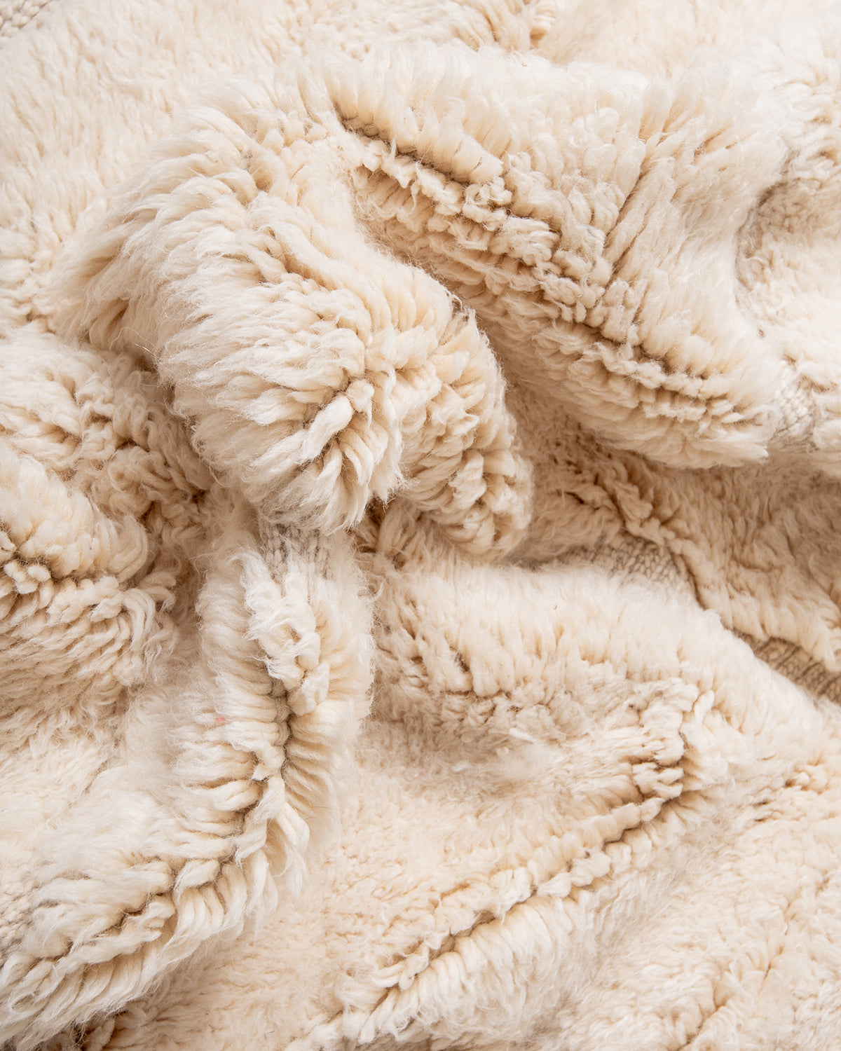 Thick fluffy wool of cream M'rirt rug bunched up to show texture.