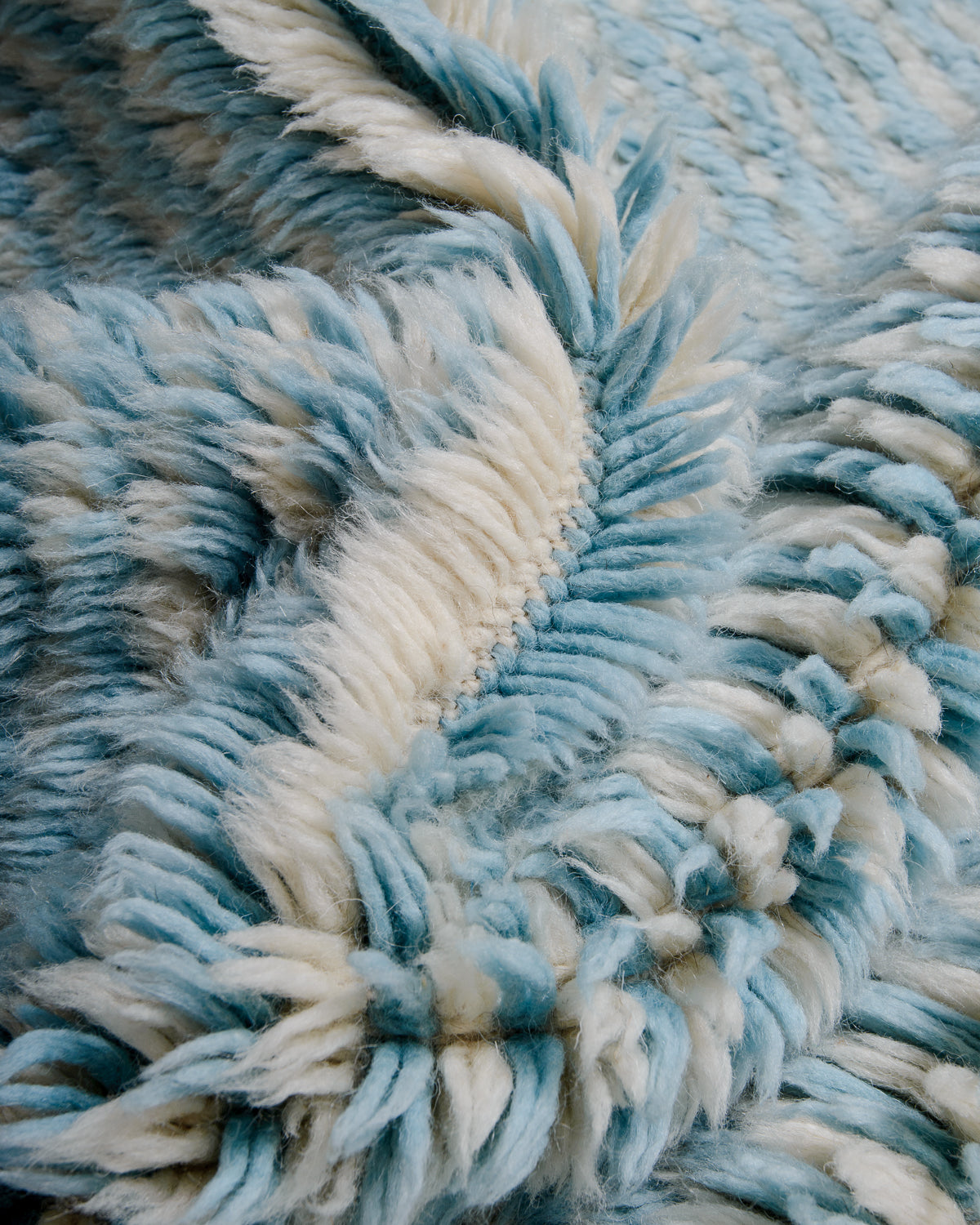 Detail of knots and pile in cream and light blue wool rug.