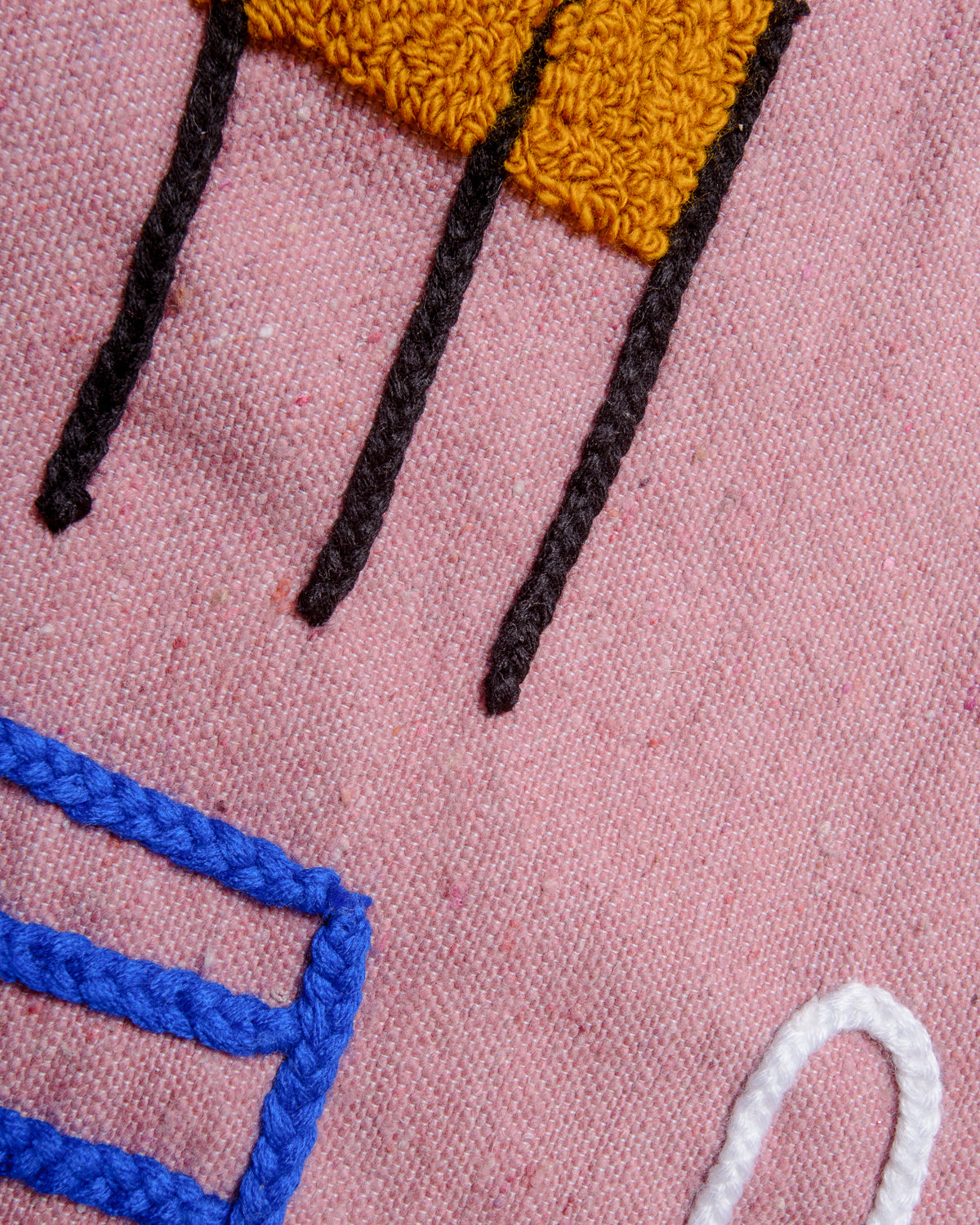 Detail of pink wool cushion cover with hand embroidered abstract design.