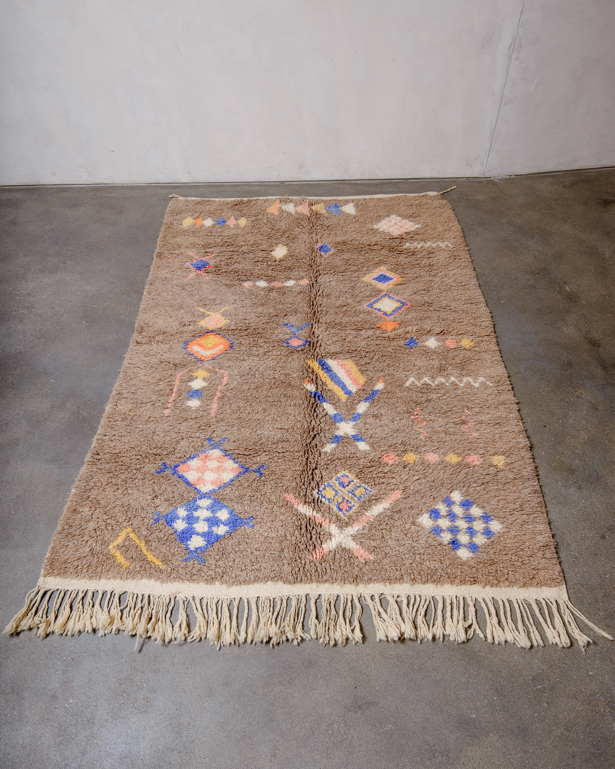 Berberlin Vintage Berber Rug made of fluffy brown wool, laying on a grey cement floor.