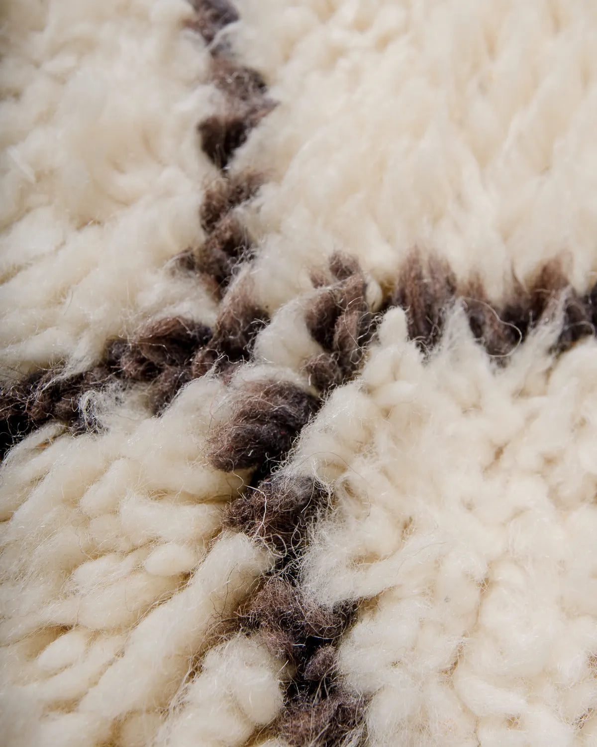 Detail of wool Berber rug in cream wool and grey-brown coloured design.