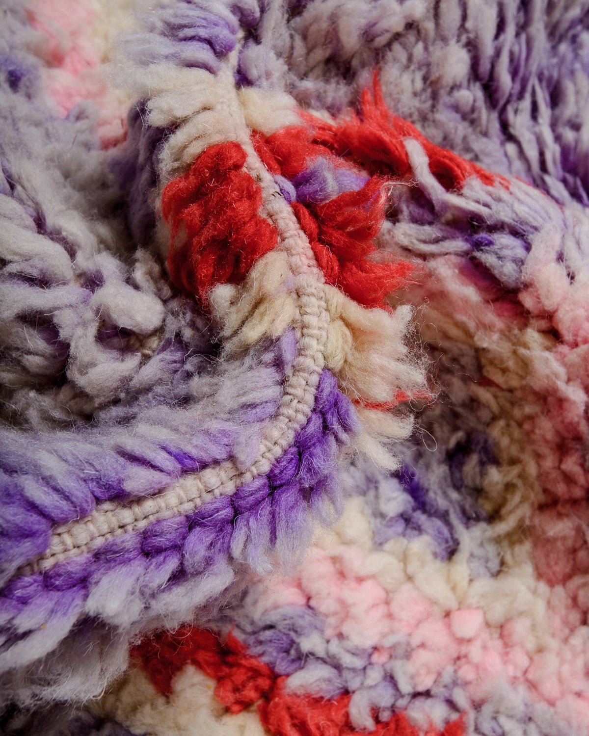 Detail of Berberlin Vintage Berber Rug made of fluffy lavender, red, pink and cream wool.