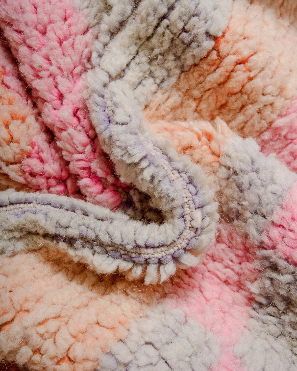 Detail of Berberlin Vintage Berber Rug made of fluffy wool in pink, apricot and lavender.