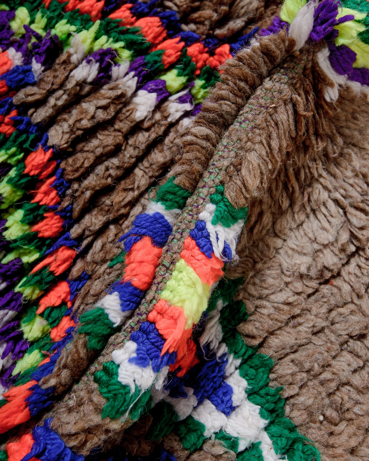Detail of Vintage Berber Rug made of brown wool with design details in neon, purple, blue, green cotton.