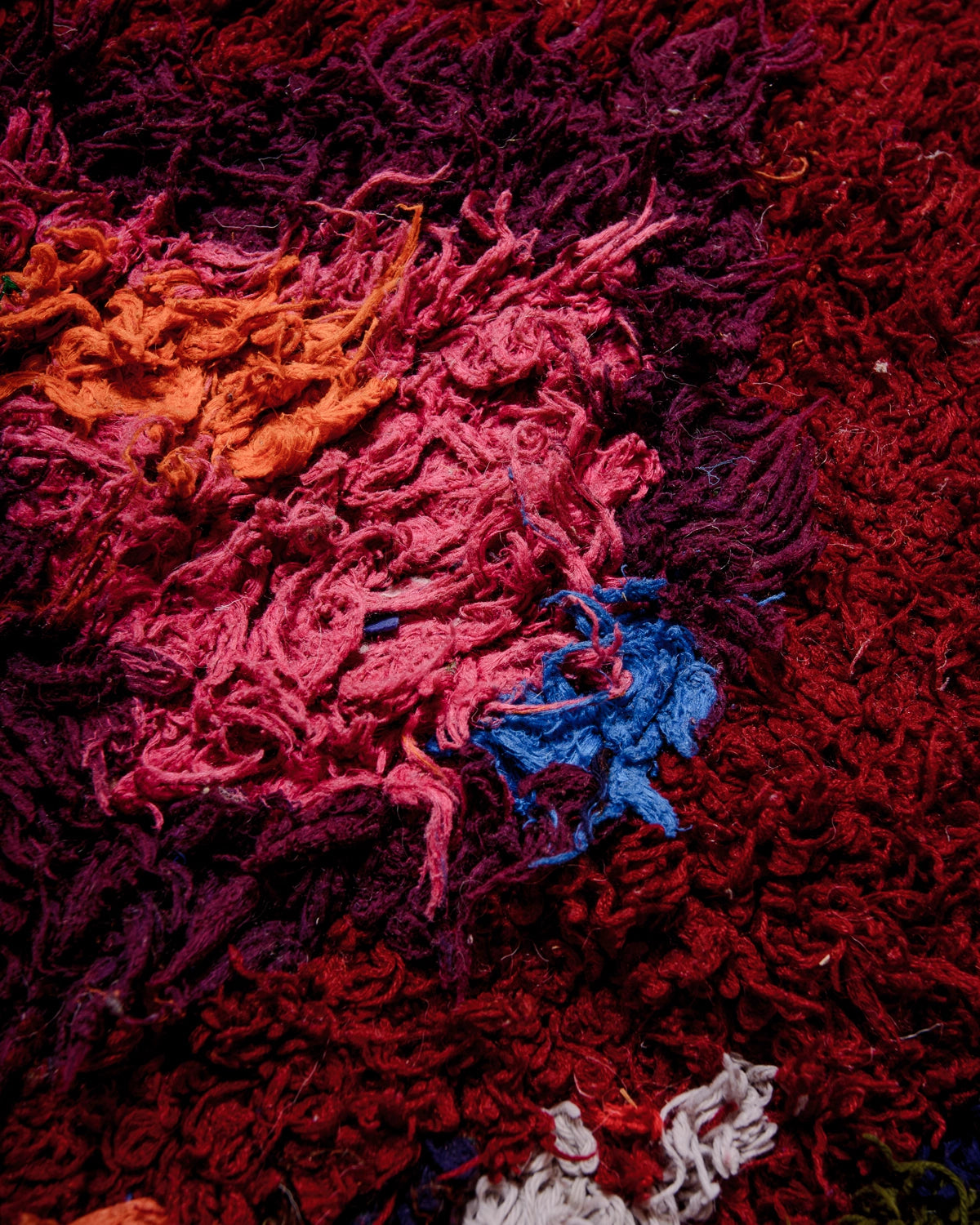 Detail of Berberlin Vintage Berber Rug in shaggy shades of red, pink, navy, khaki, burgundy.