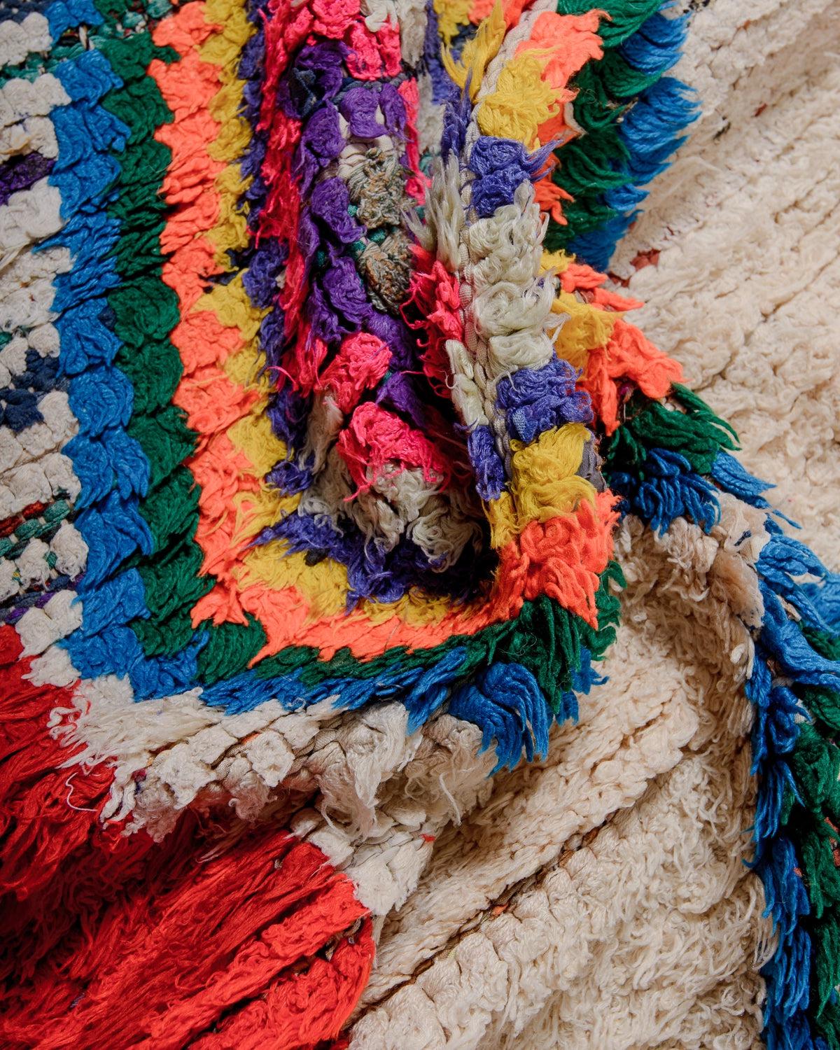 Detail of Berberlin Vintage Berber Rug in shades of red, cream, grey and blue with coloured diamond motifs in the center.