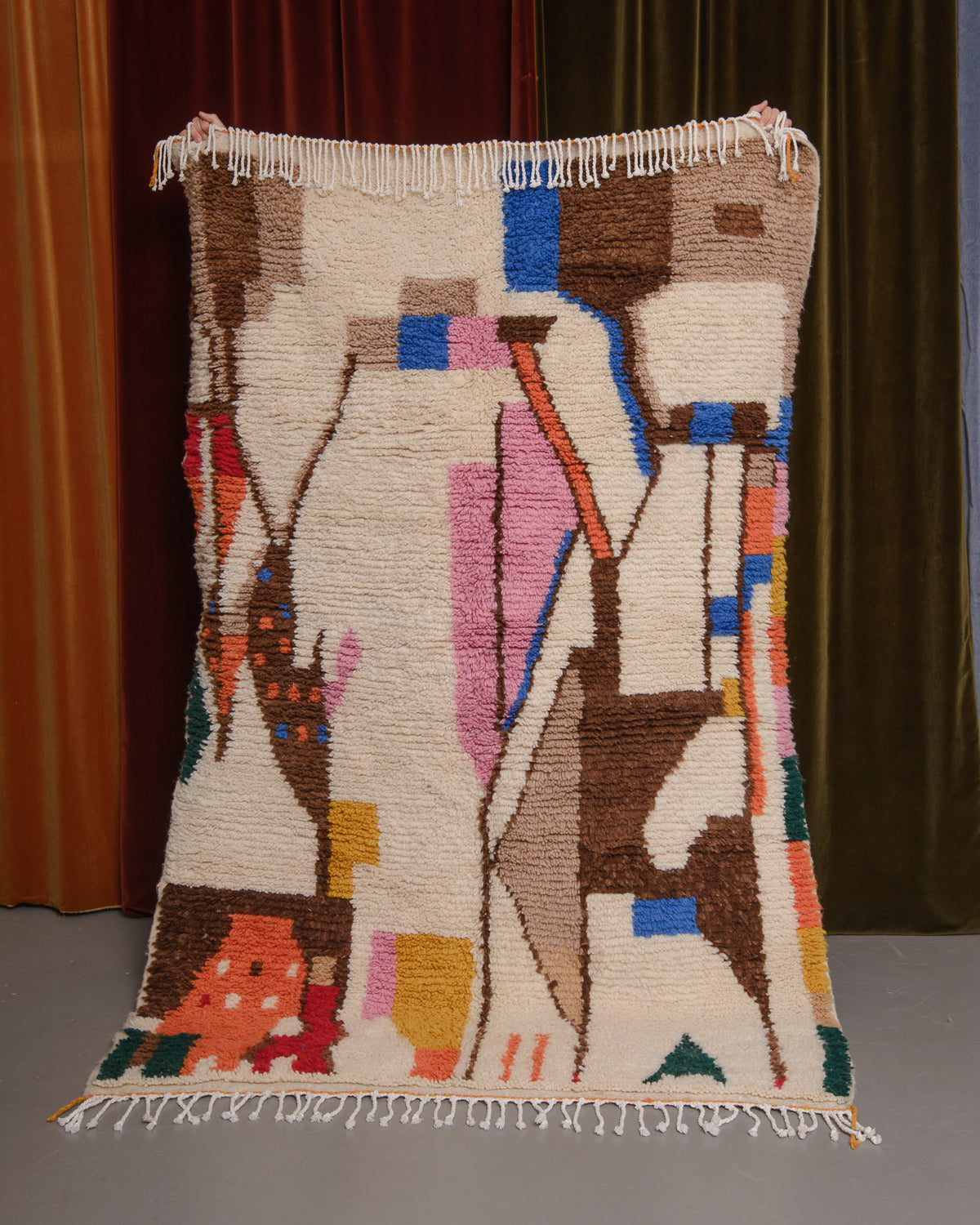 Azilal rug held in front of velvet curtains. 