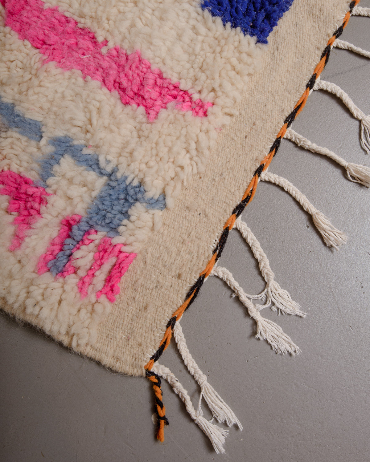 Corner of Berberlin azilal rug with white cotton tassels.
