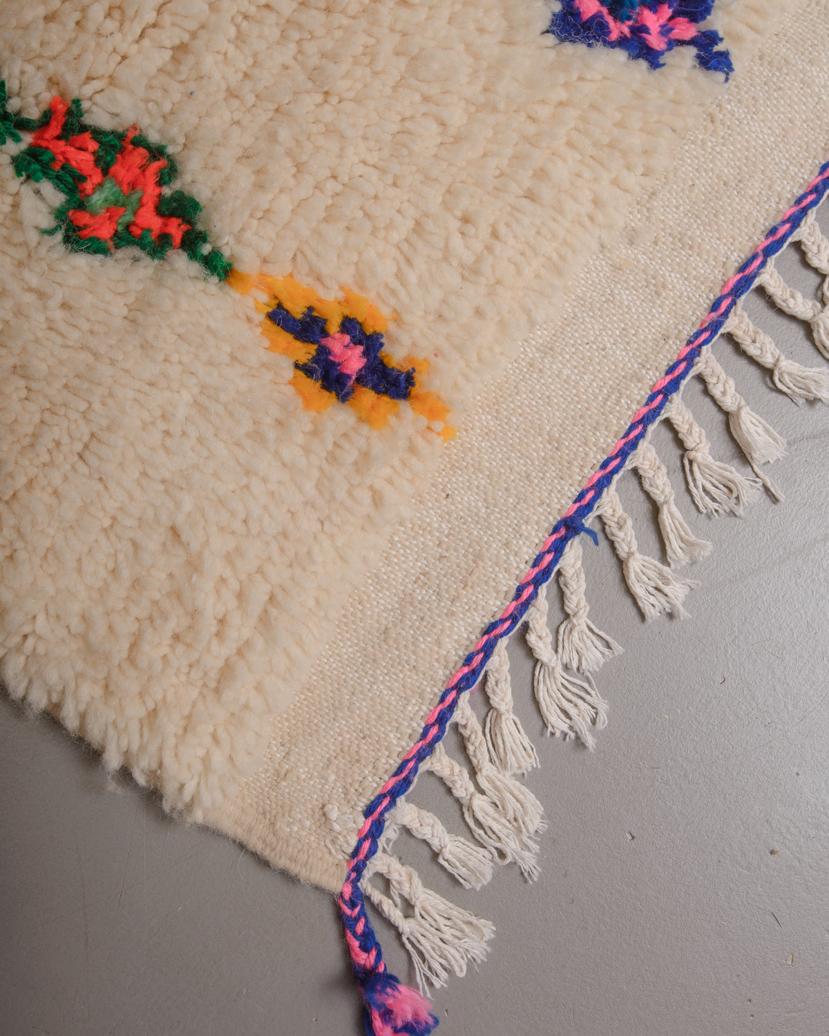 Corner of Berberlin azilal rug with white cotton tassels.