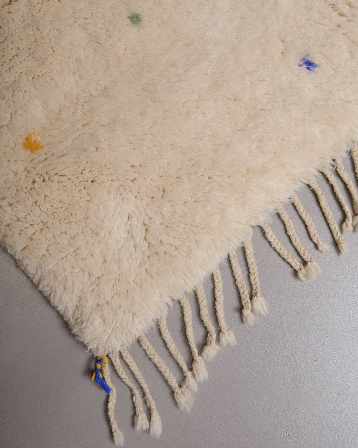 Corner of rug with cream wool and natural wool tassels.