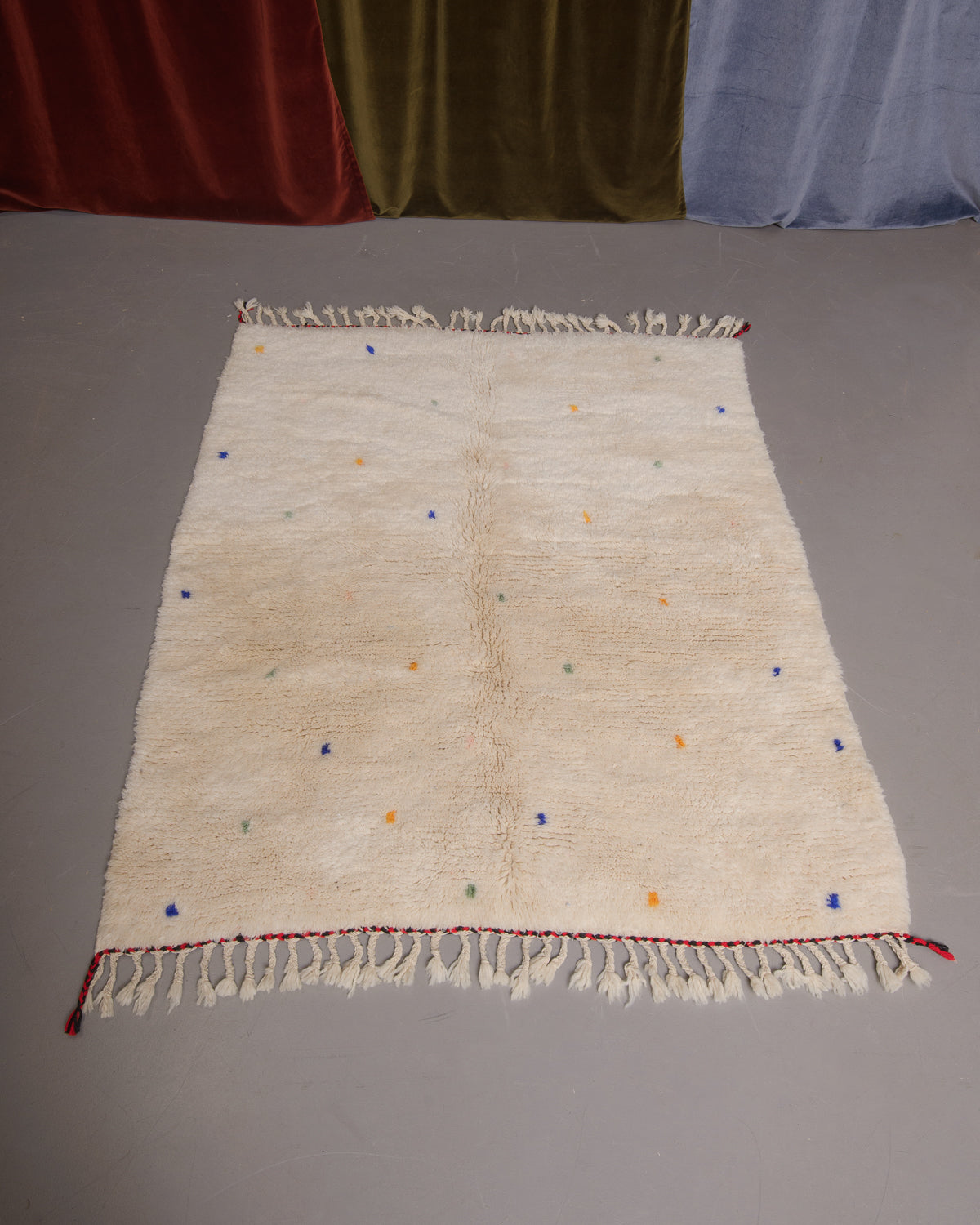Berberlin Finest rug with cream wool and softly coloured dots, on a grey floor. 