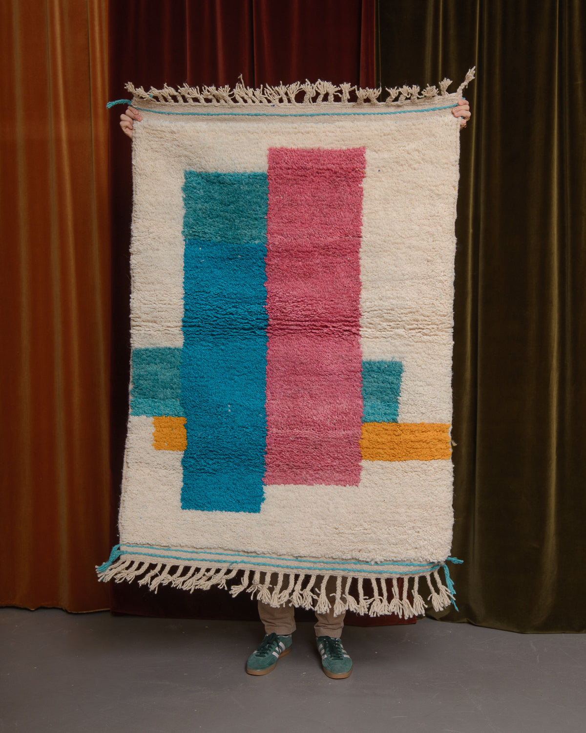Berberlin Special Edition Beniourain rug held up in front of a velvet curtain.