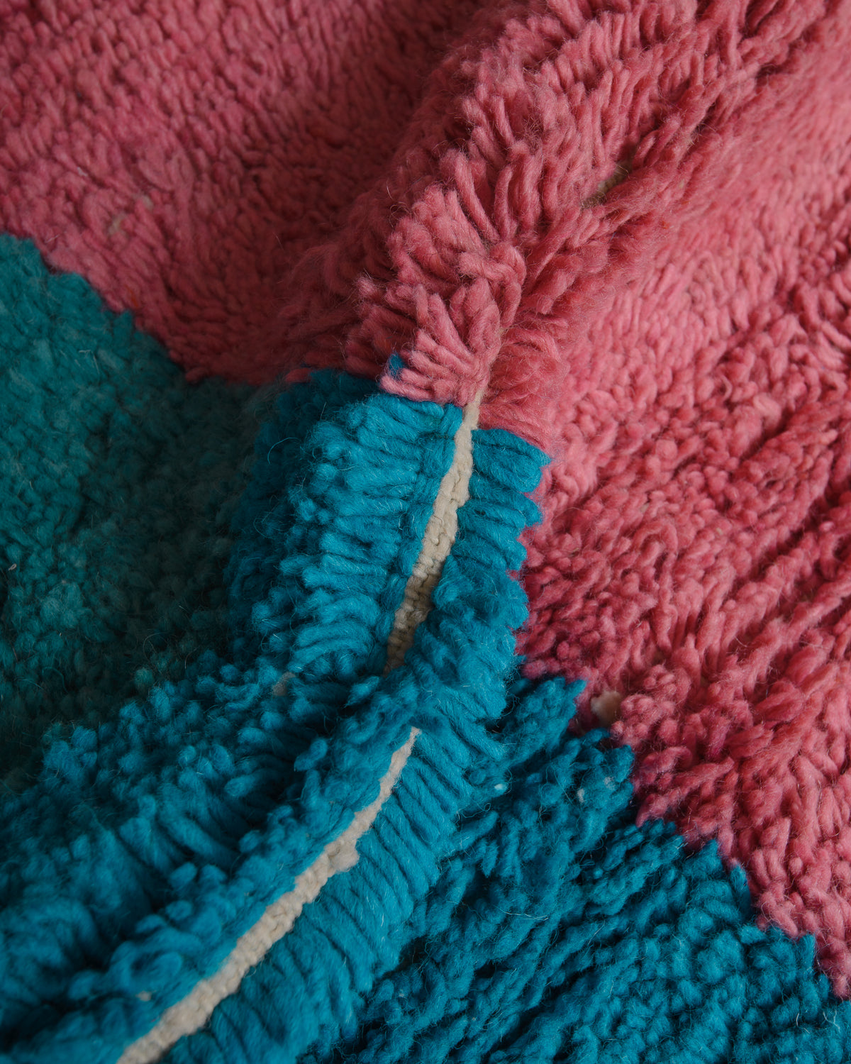 Close up of wool rug with blue and pink. 