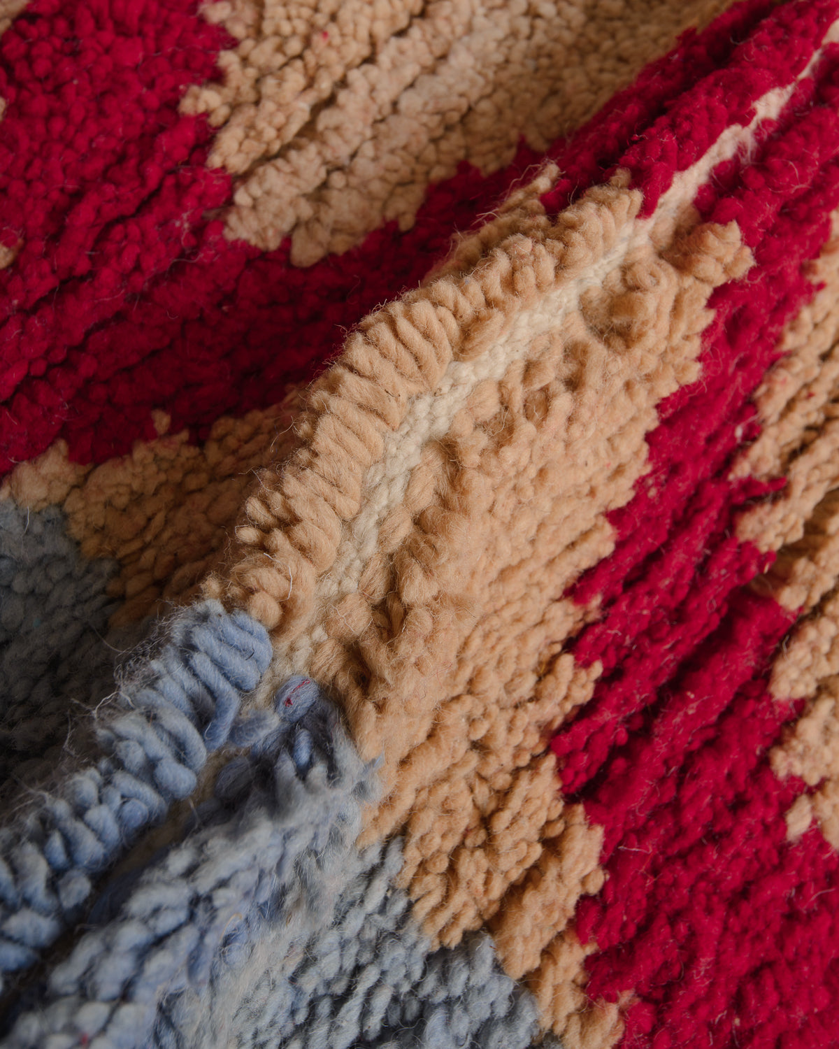 Close up of wool rug with light blue, sand and red. 