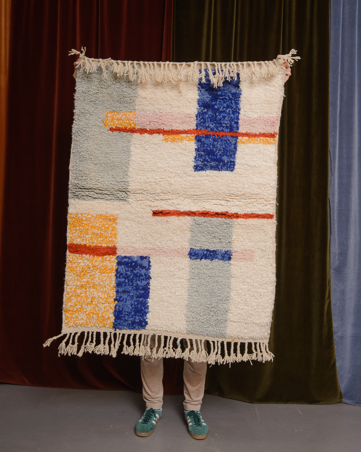 Berberlin Special Edition Beniourain rug held up in front of a velvet curtain.