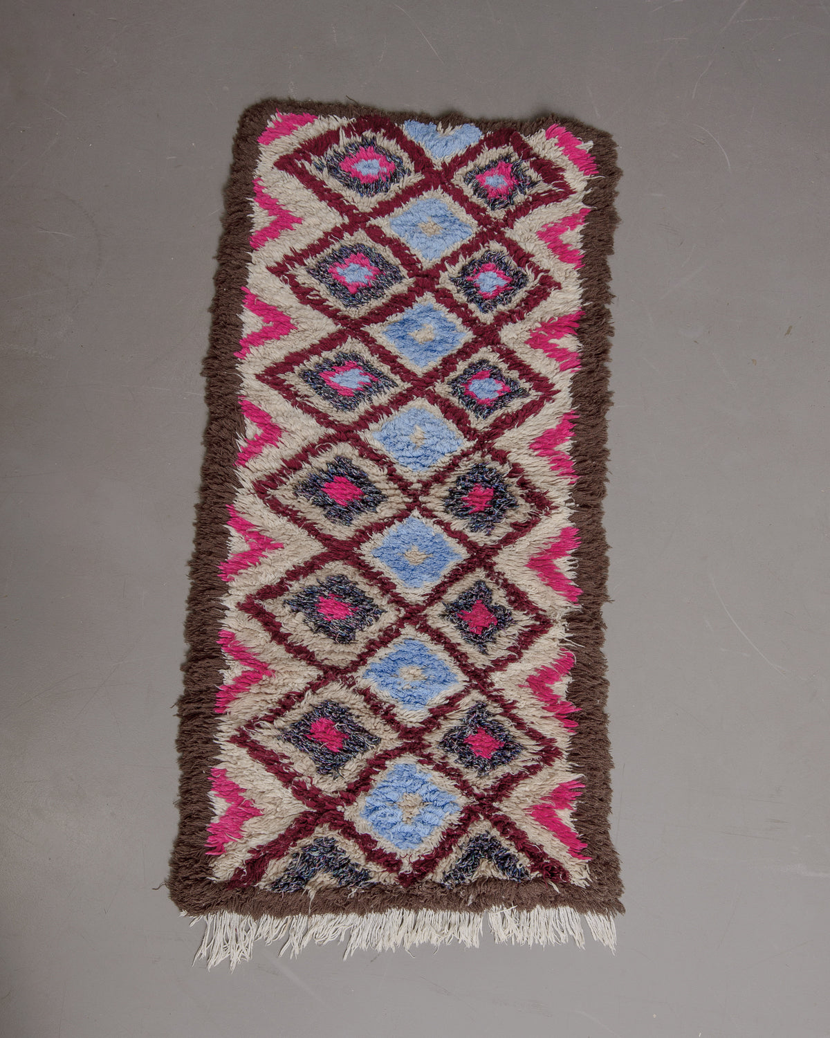 Vintage Berberlin boucherouite runner rug on grey floor.