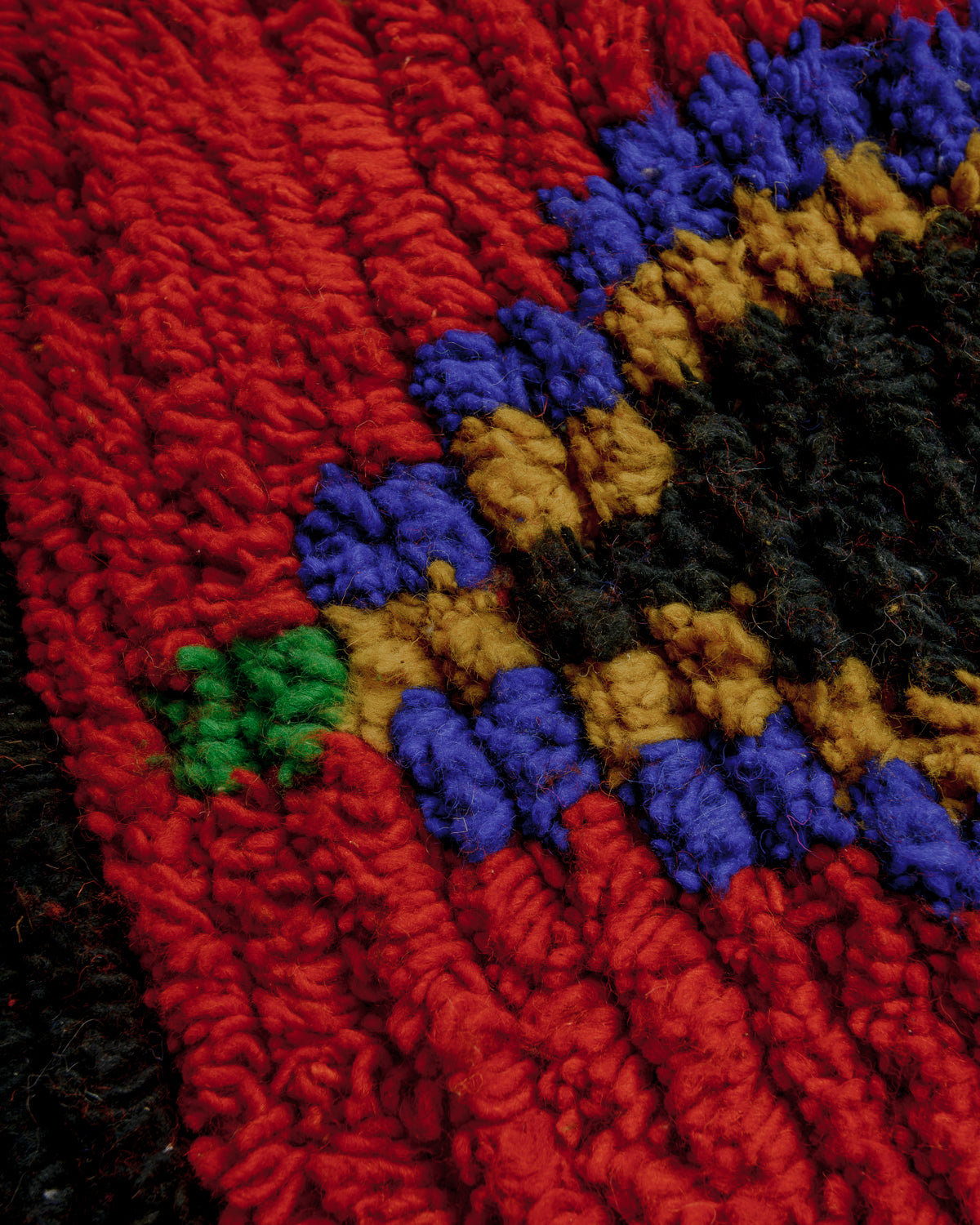 Texture of boujaad rug with beige, red, yellow, black and blue wool.