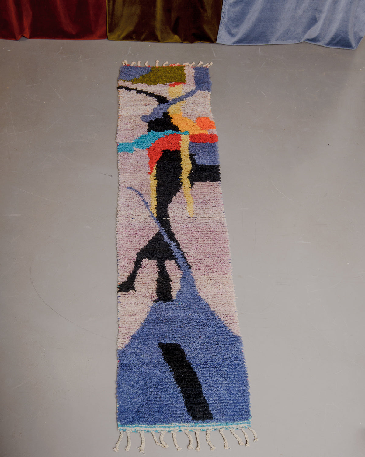 Vintage Berberlin boujaad runner rug on grey floor in front of velvet curtains.