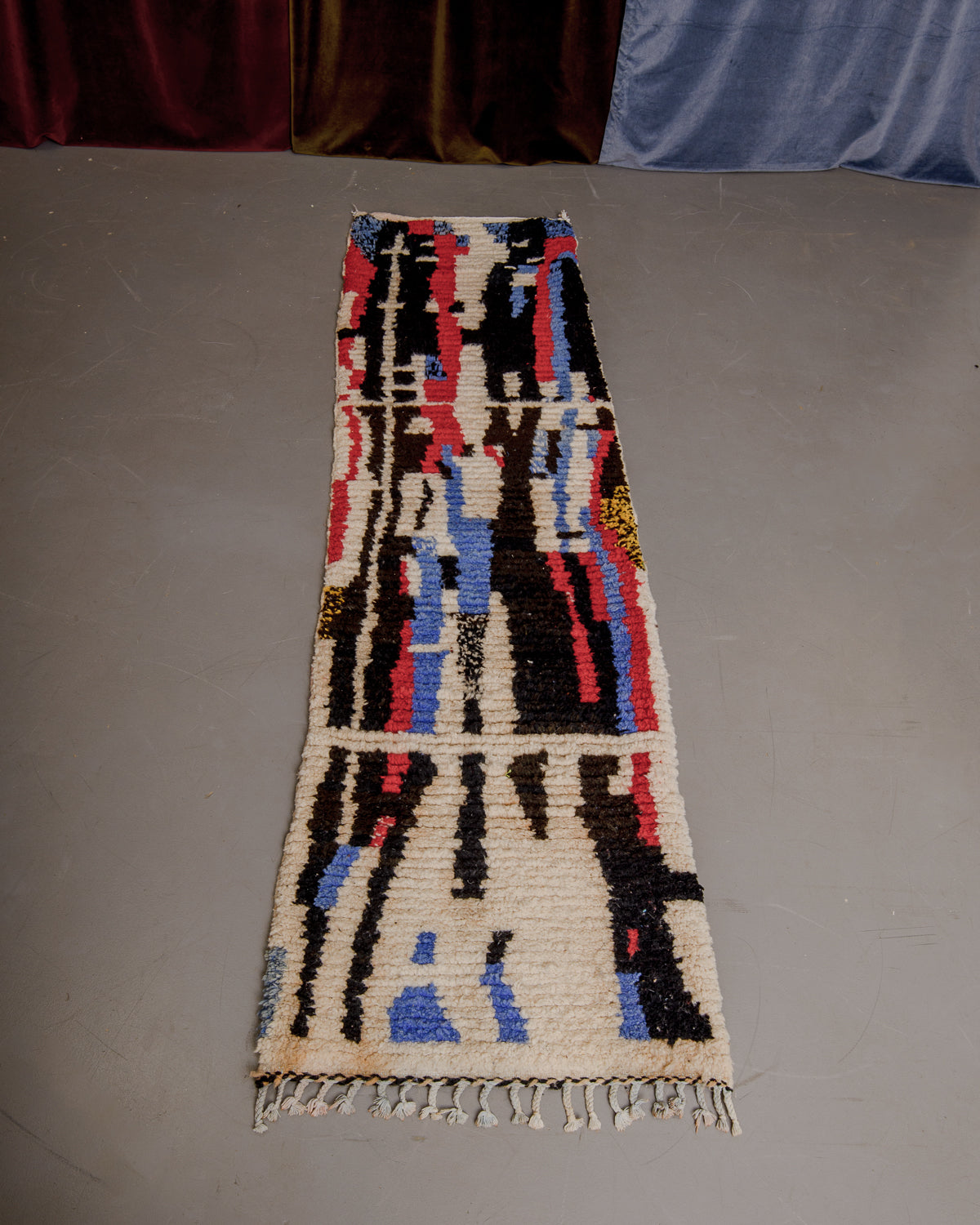 Vintage Berberlin boujaad runner rug on grey floor in front of velvet curtains.