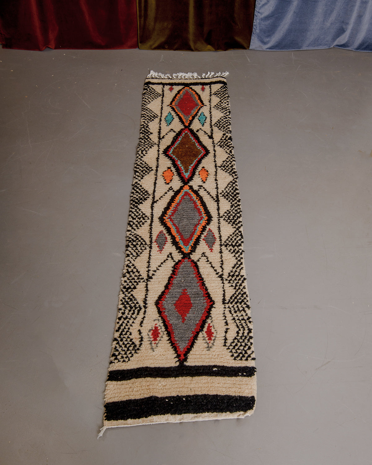 Vintage Berberlin boujaad runner rug on grey floor in front of velvet curtains.