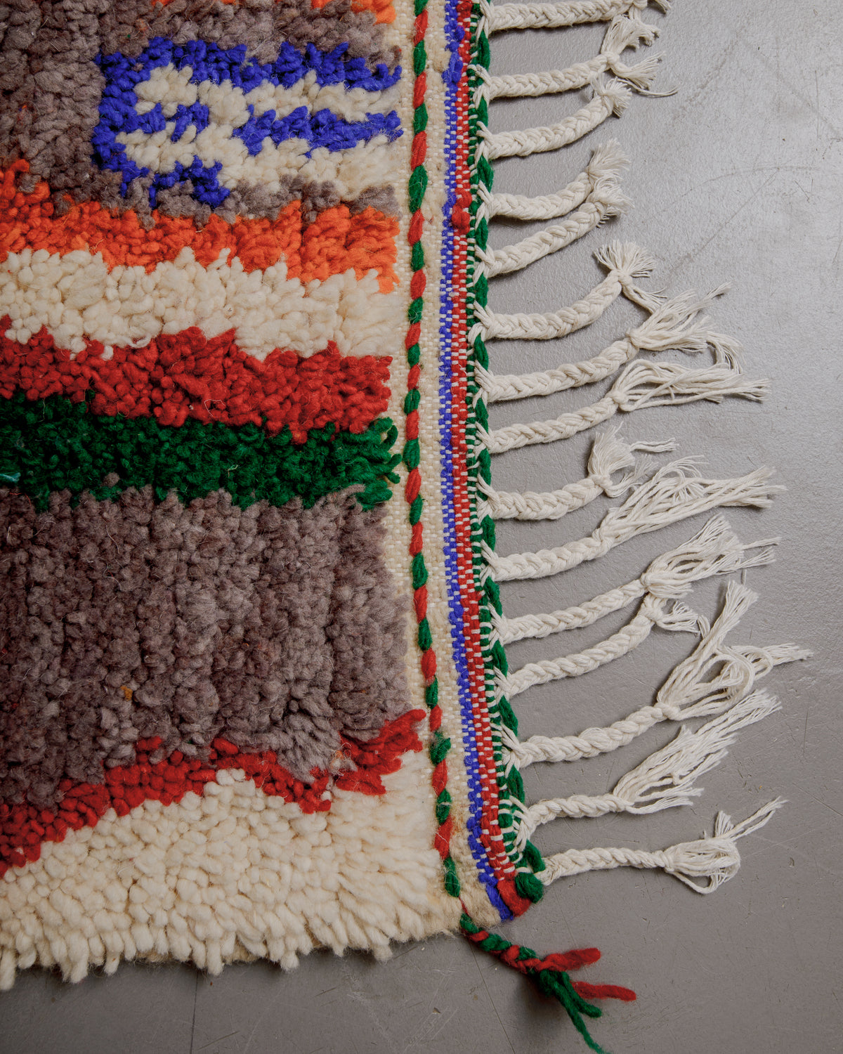 Edge of boujaad rug with white cotton tassels.