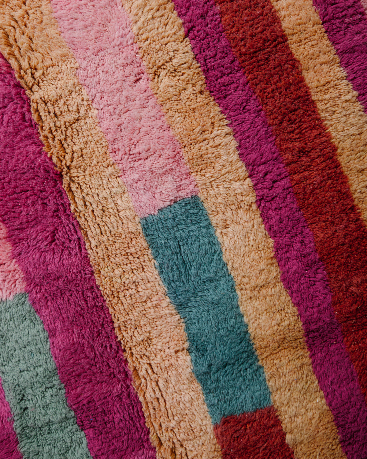 Surface of rug with stripes in pink, magenta, brown and turquoise. 