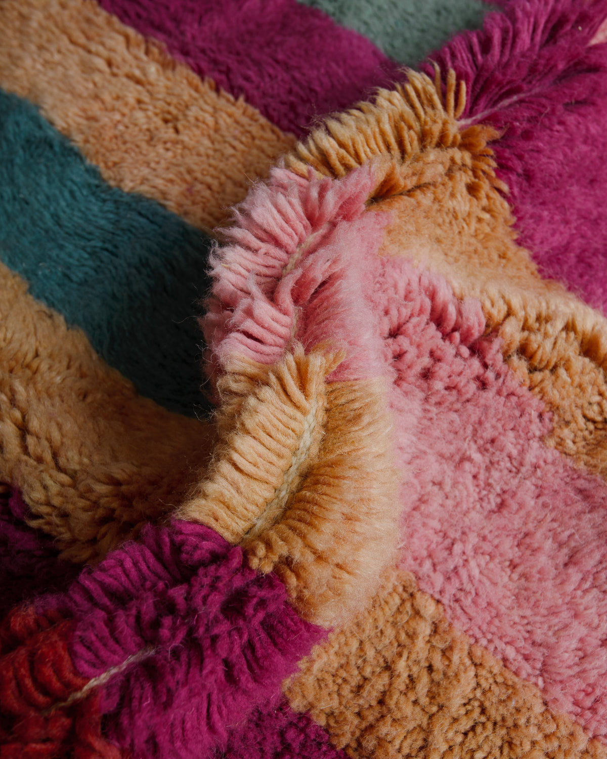 Close up of plush wool pile in pink, sand, magenta and turquoise.