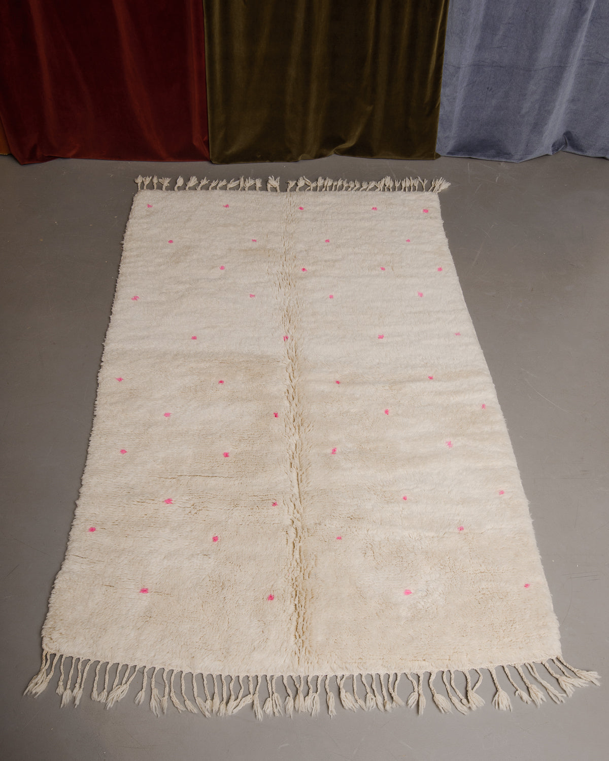 Berberlin Finest beniourain rug on grey floor in front of velvet curtains.