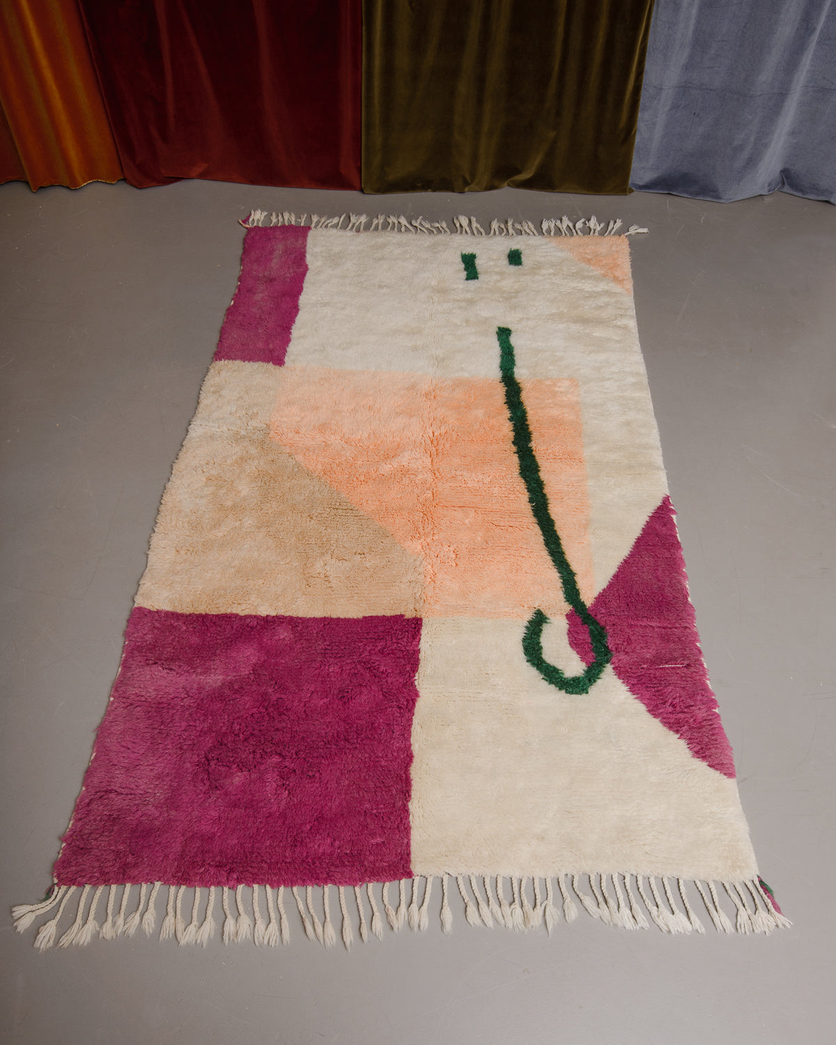 Berberlin Finest beniourain rug on grey floor in front of velvet curtains.