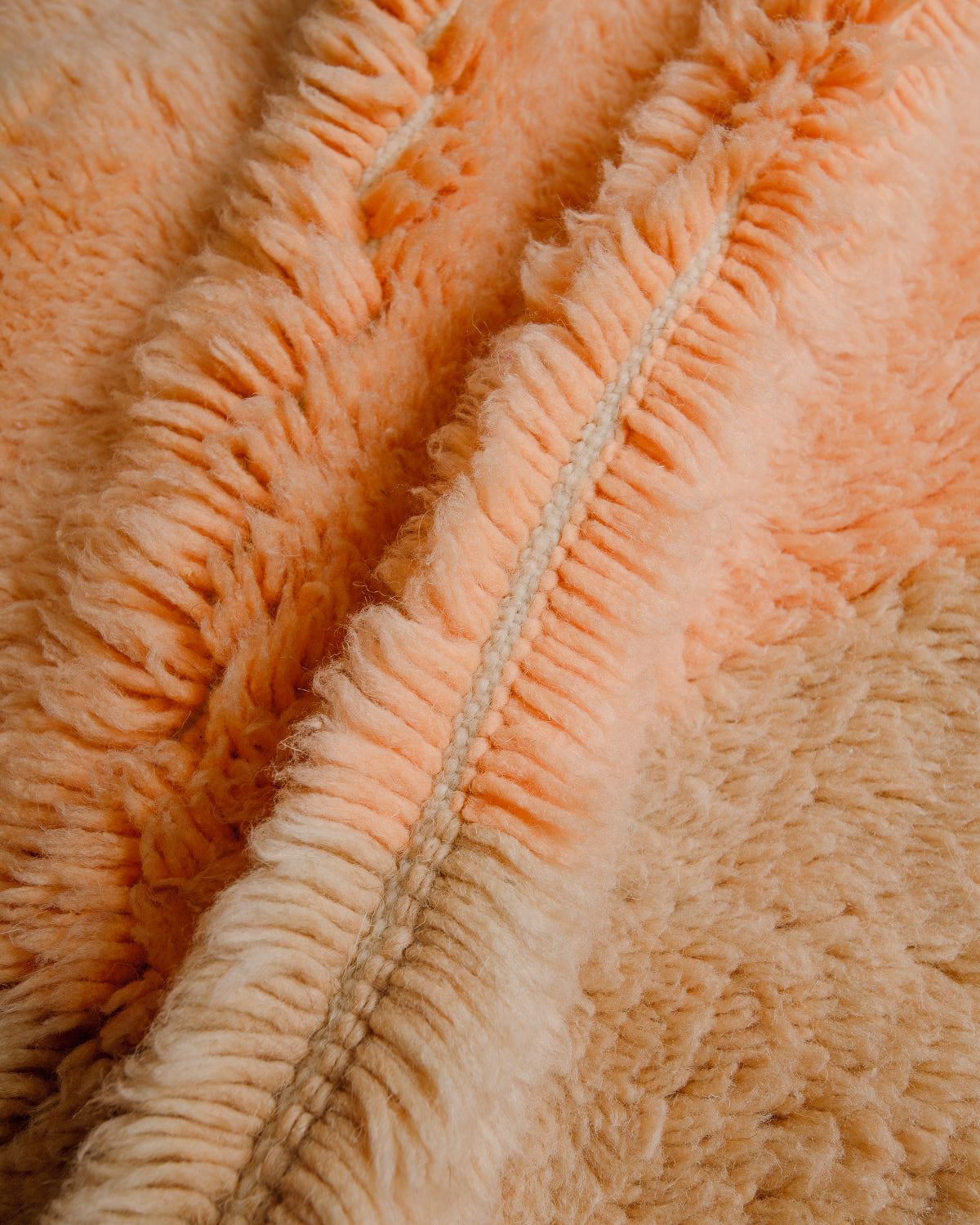 Close up of plush wool pile in apricot and sand.