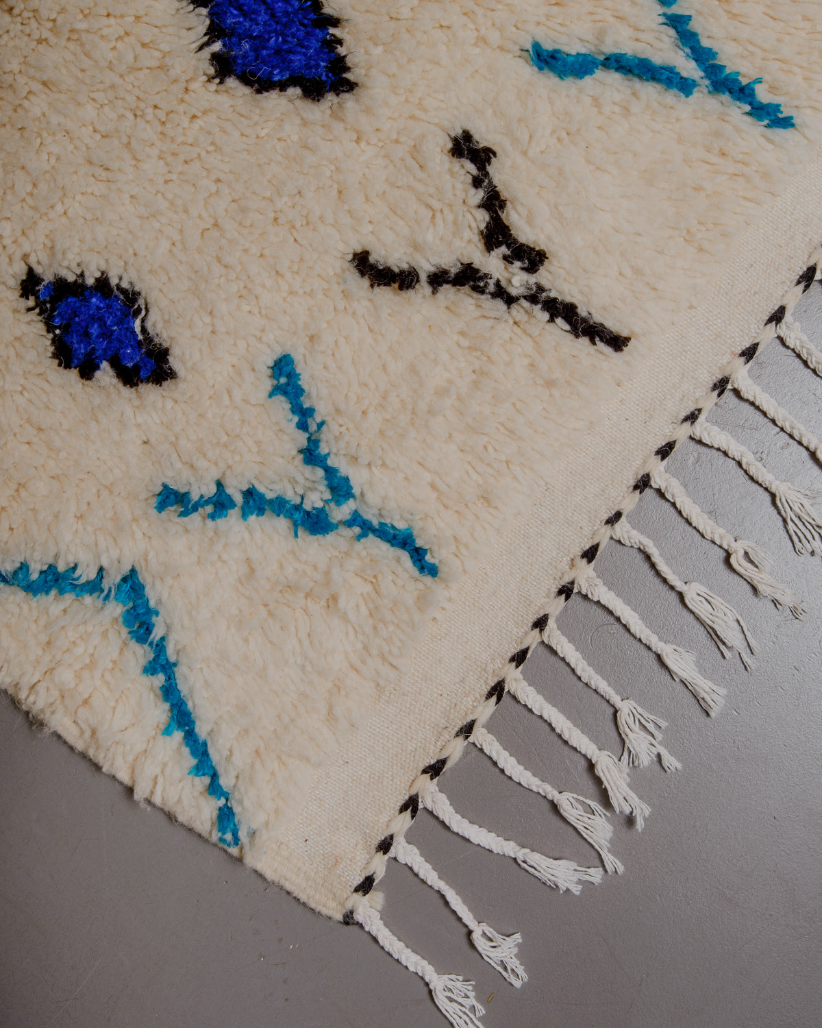 Corner of azilal rug with white cotton tassels.