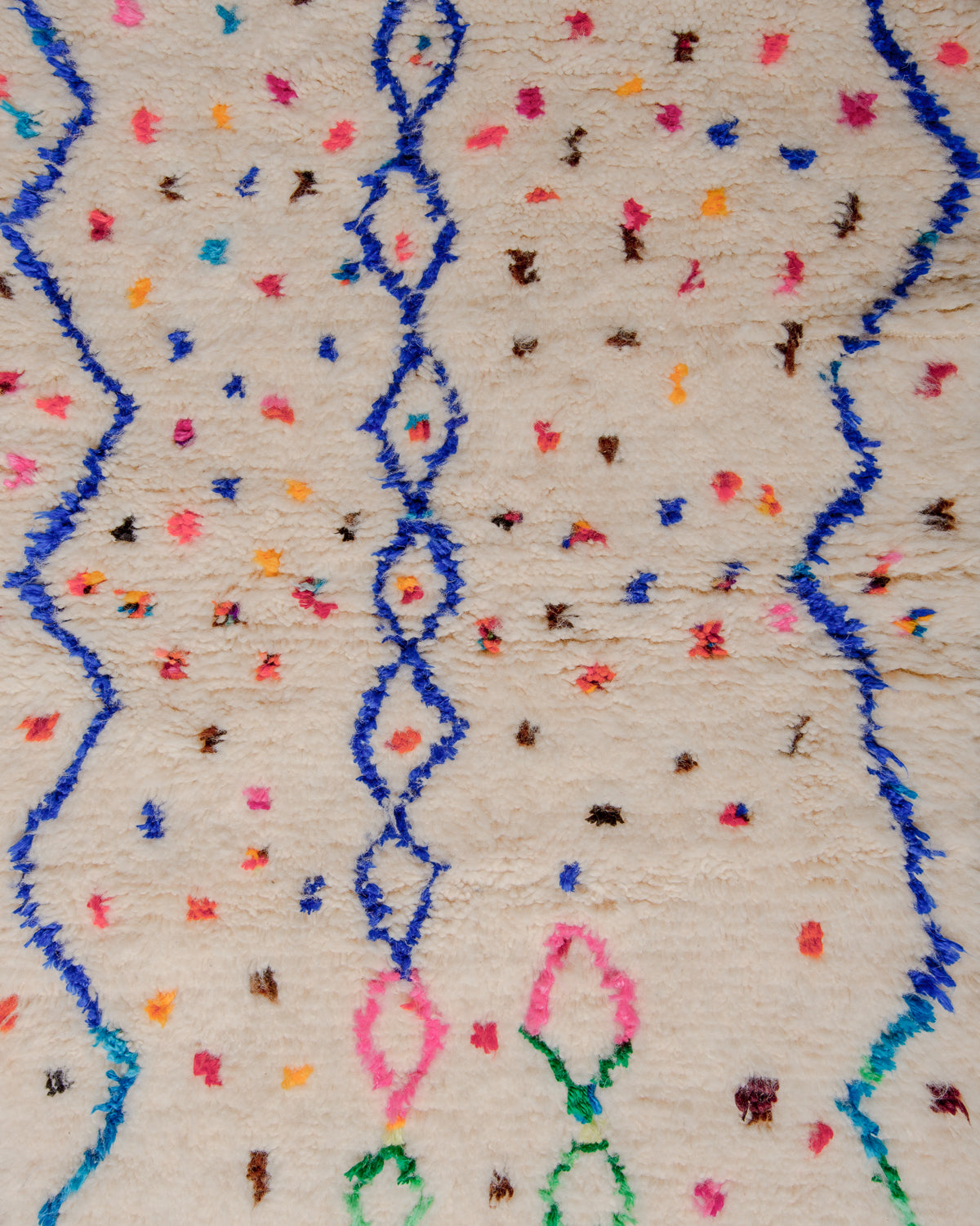 Surface of rug with cream wool and blue lines and colourful dots in cotton.