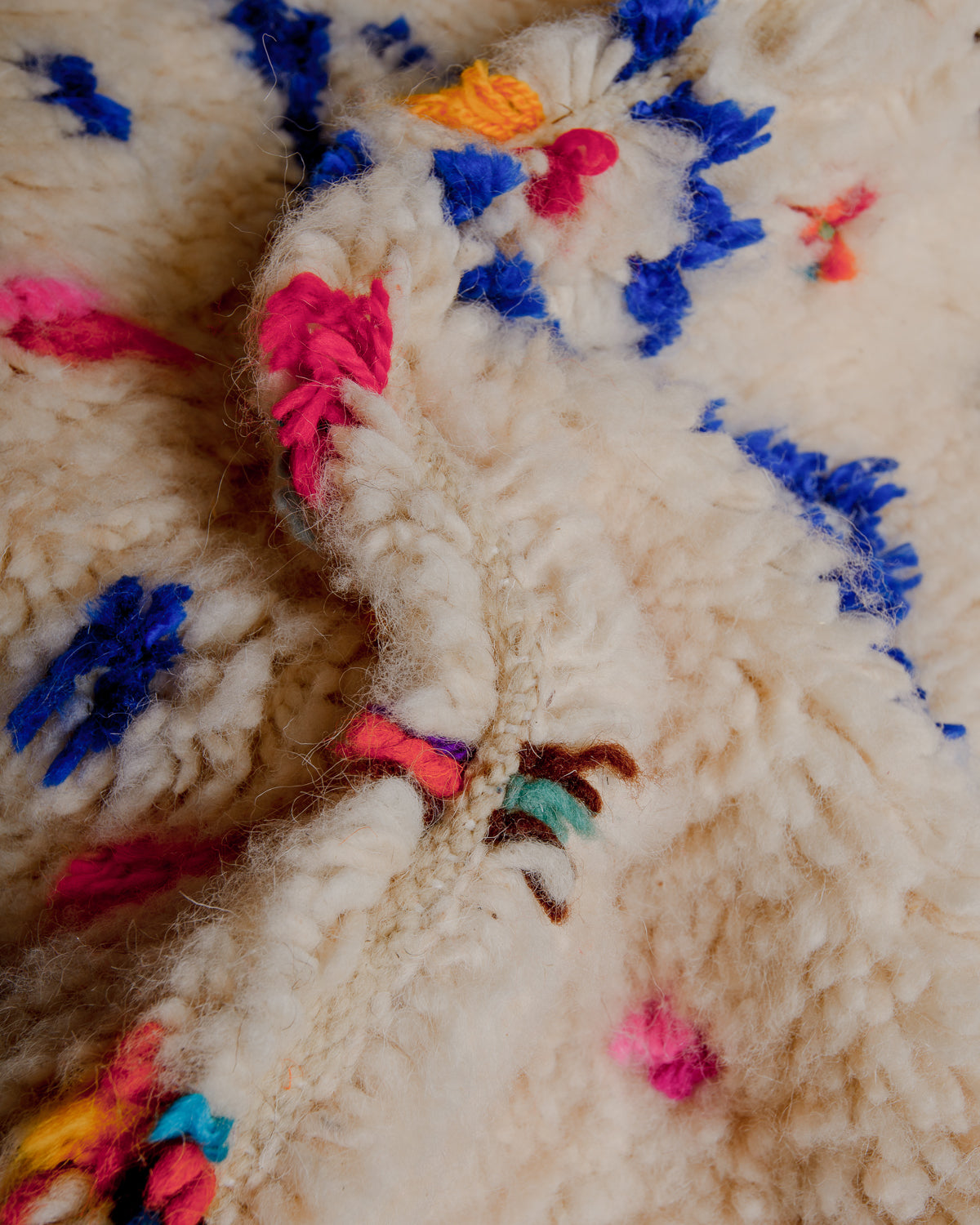 Close up of cream wool rug with colourful details in wool and cotton.