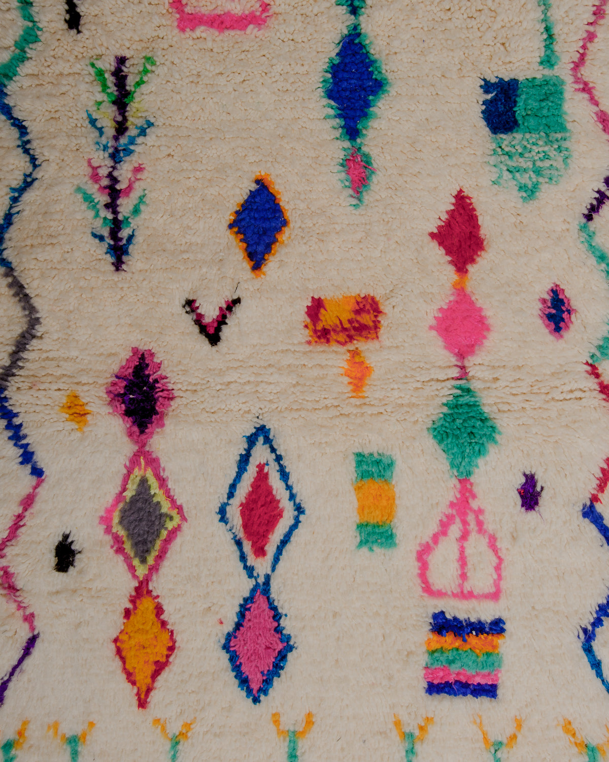 Surface of rug with cream wool base and colourful pattern of symbols and lines in dyed wool and cotton.