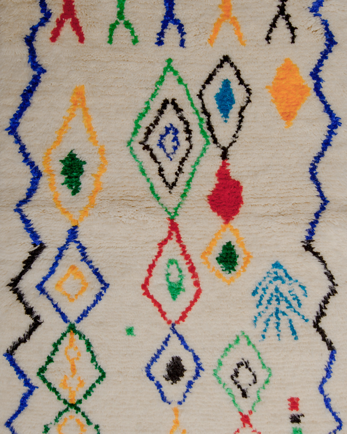 Surface of rug with cream wool base and colourful pattern of symbols and lines in dyed cotton in red, green, yellow, black and blue.