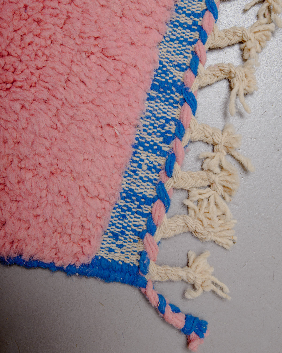 Corner of rug with wool tassels and a flat woven edge.