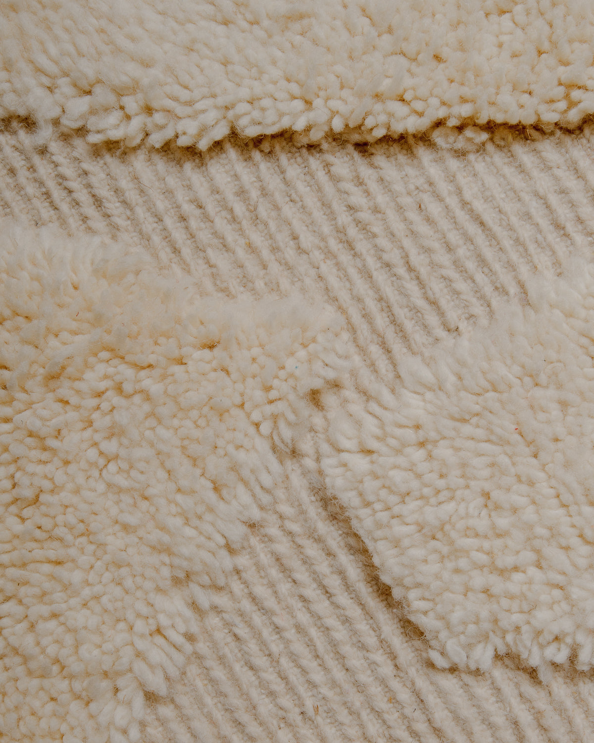Surface of wool rug with a combination of fluffy pile and flat woven areas that are embroidered with fine lines. 