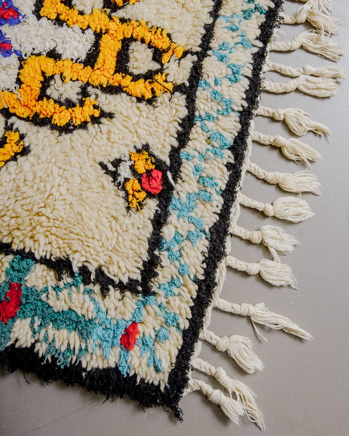 Close up of boucherouite rug surface with colourful cotton and cream wool.