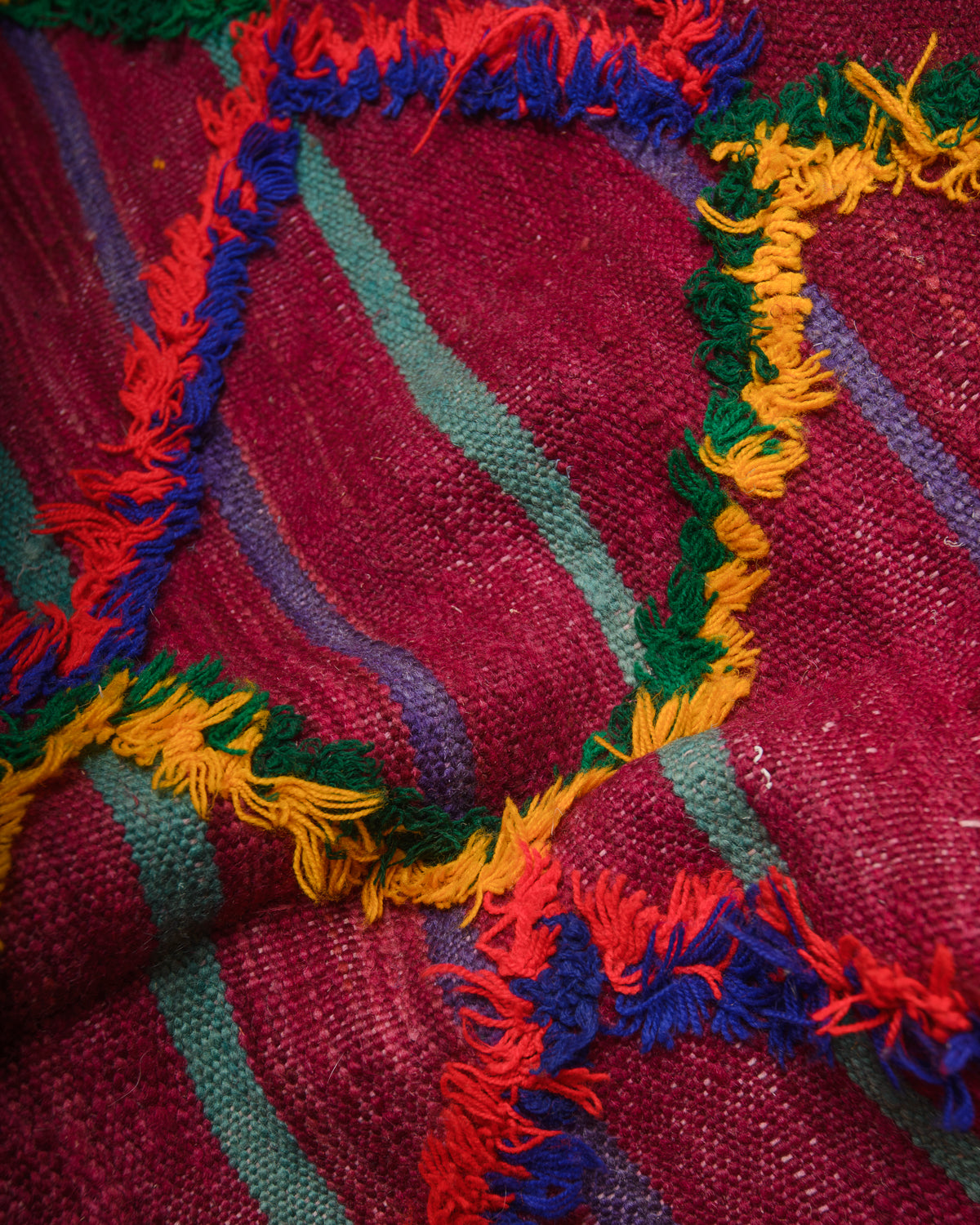 Surface of flat woven wool kelim rug with fluffy embroidered pattern.