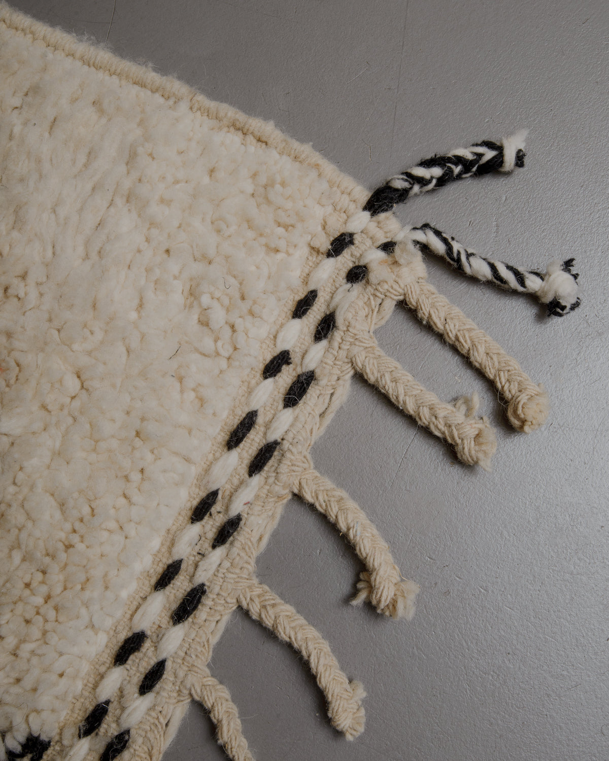 Edge of cream beniourain rug with natural wool tassels.