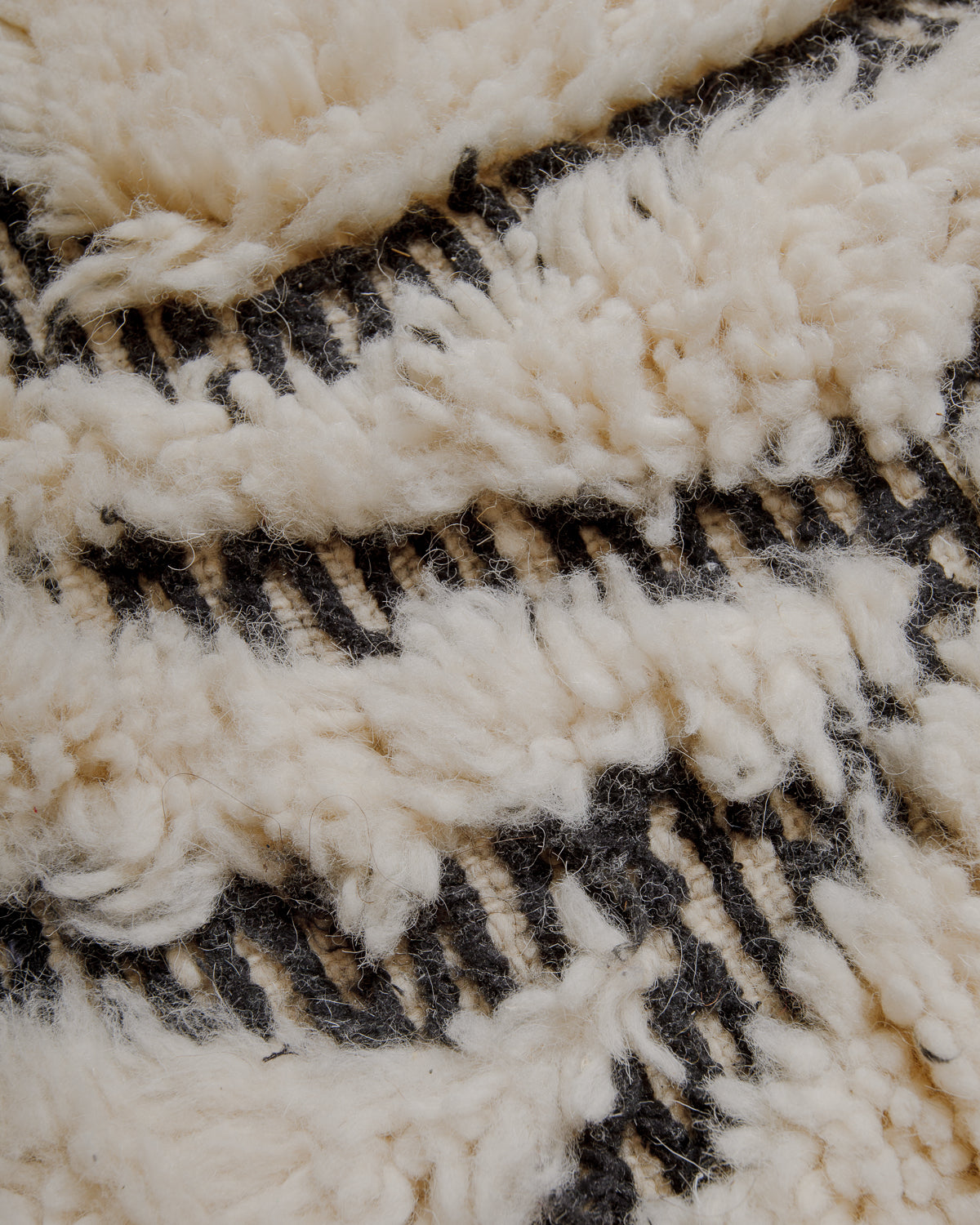 Close up of embroidered black details between cream pile.