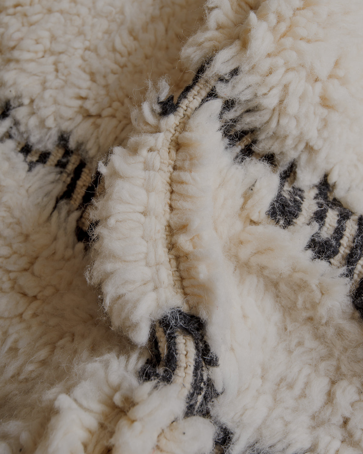 Fluffy cream wool pile with black lines  embroidered.
