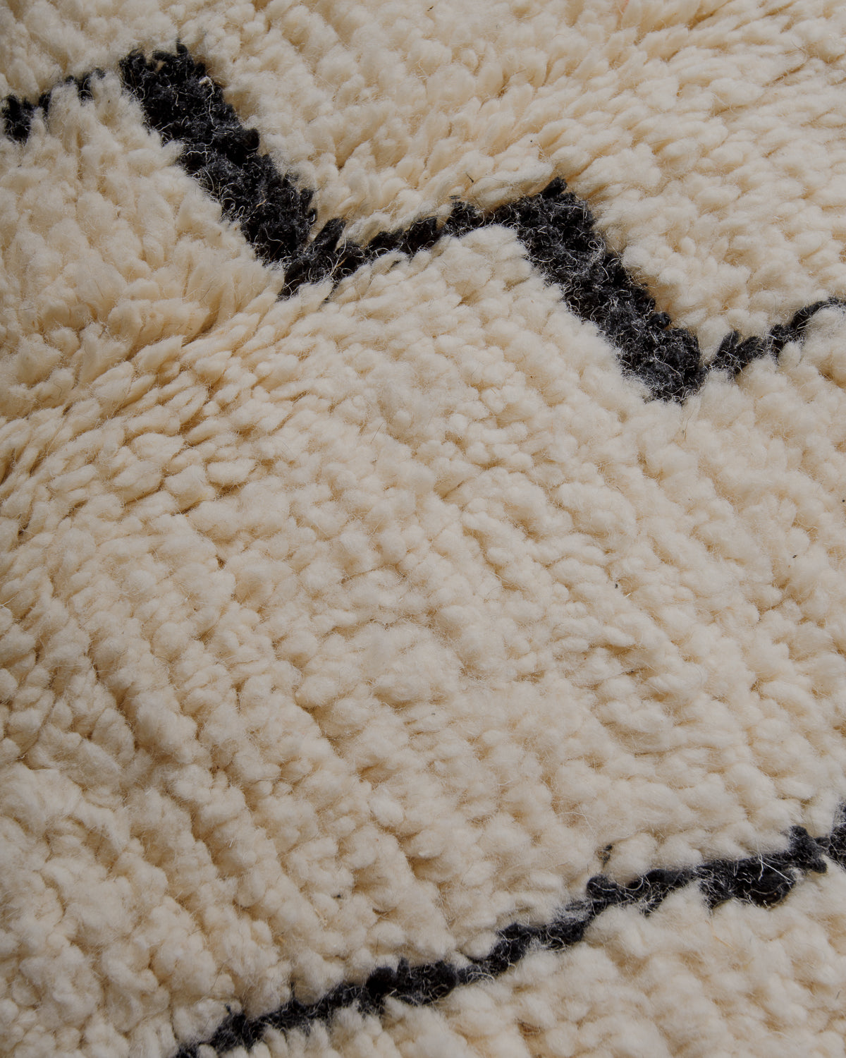 Surface of cream wool rug with pattern in black.