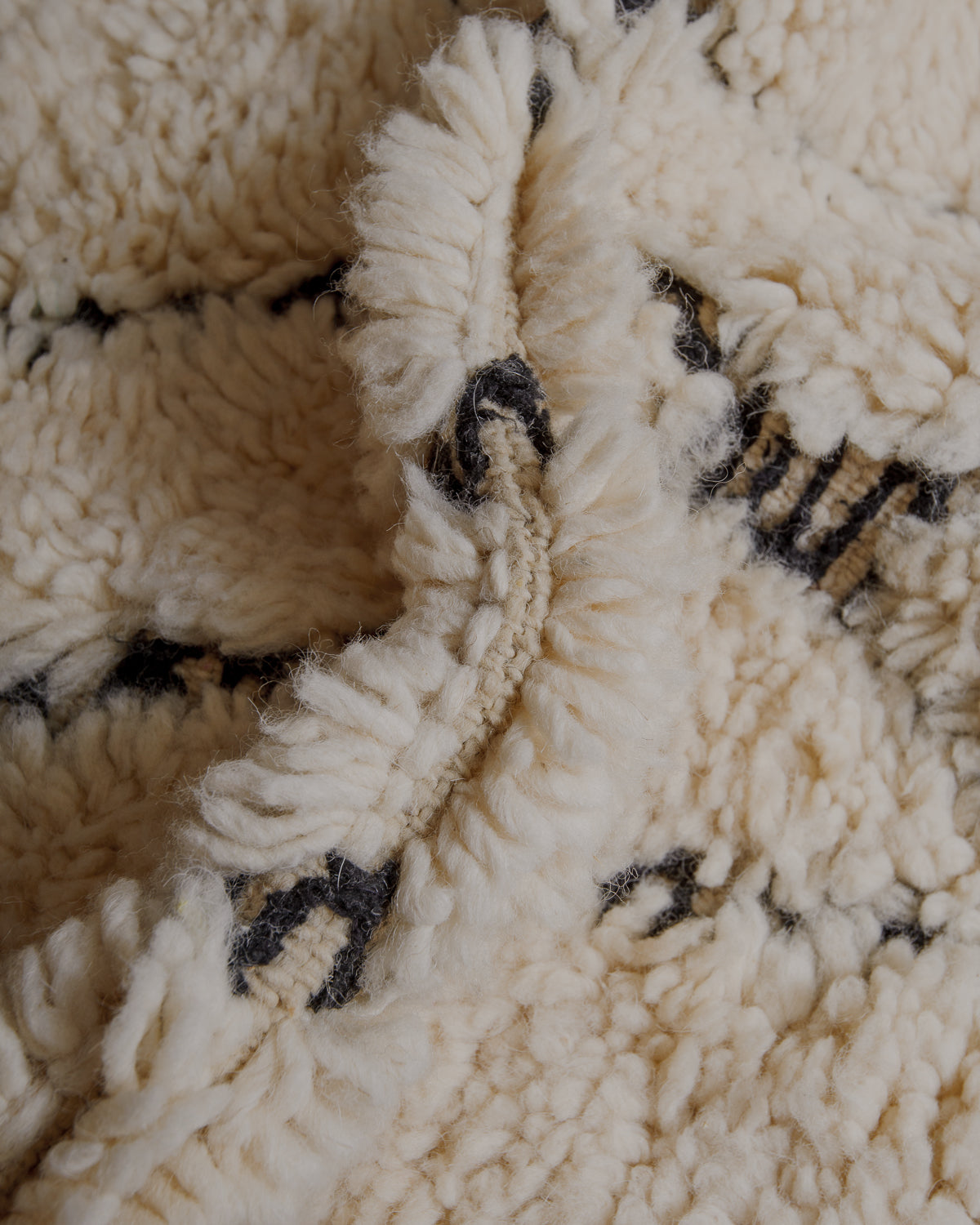 Fluffy cream wool pile with black embroidered lines .