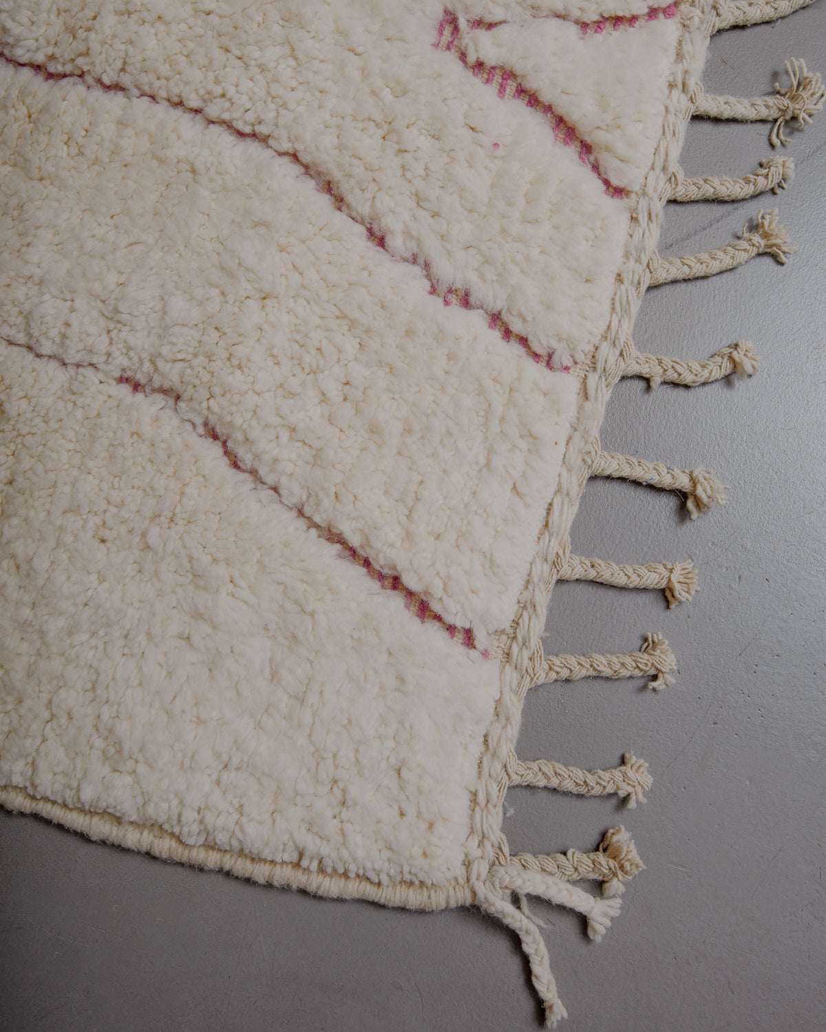 Corner of cream beniourain rug with natural wool tassels.