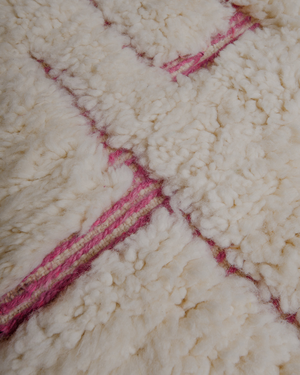 Fluffy cream wool pile with pink embroidered details.